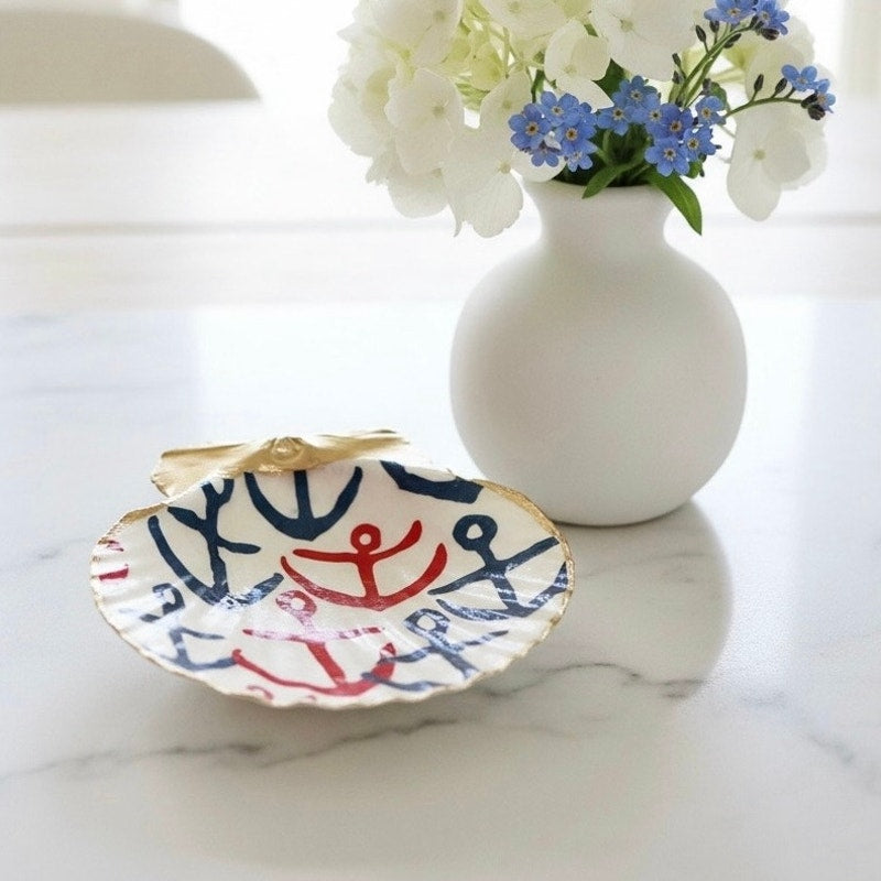 Navy and red anchor scallop shell dish styled beside white and blue flowers