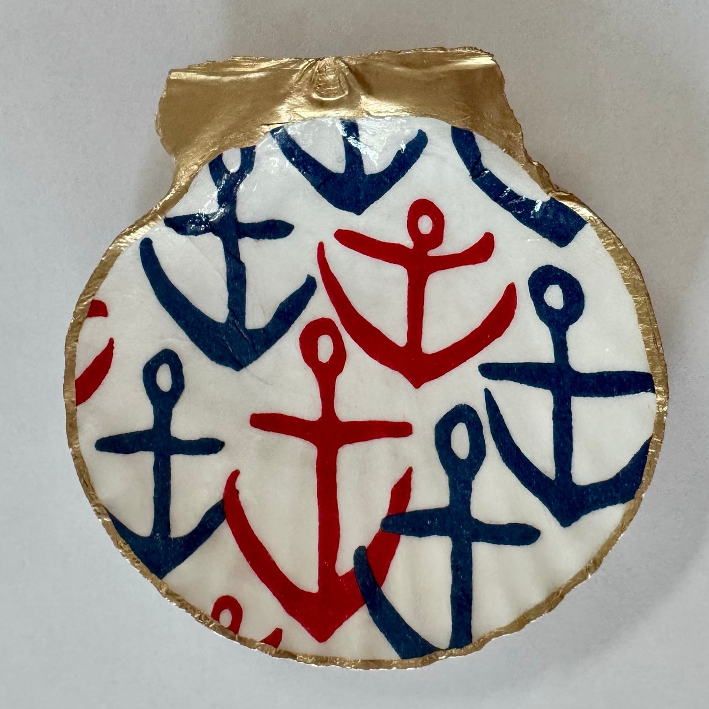 Close-up of navy and red anchor scallop shell dish with gold edging