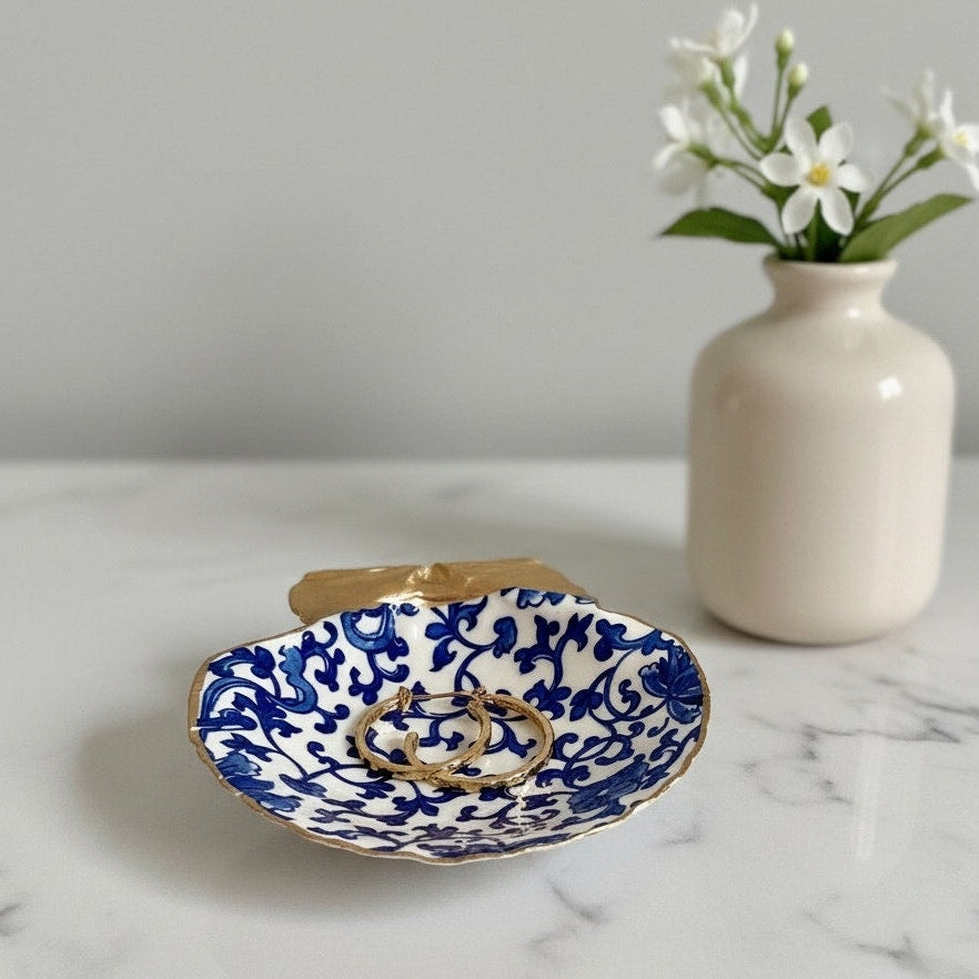 A small shell jewelry ring dish and jewelry holder with a blue and white floral pattern and gold trim